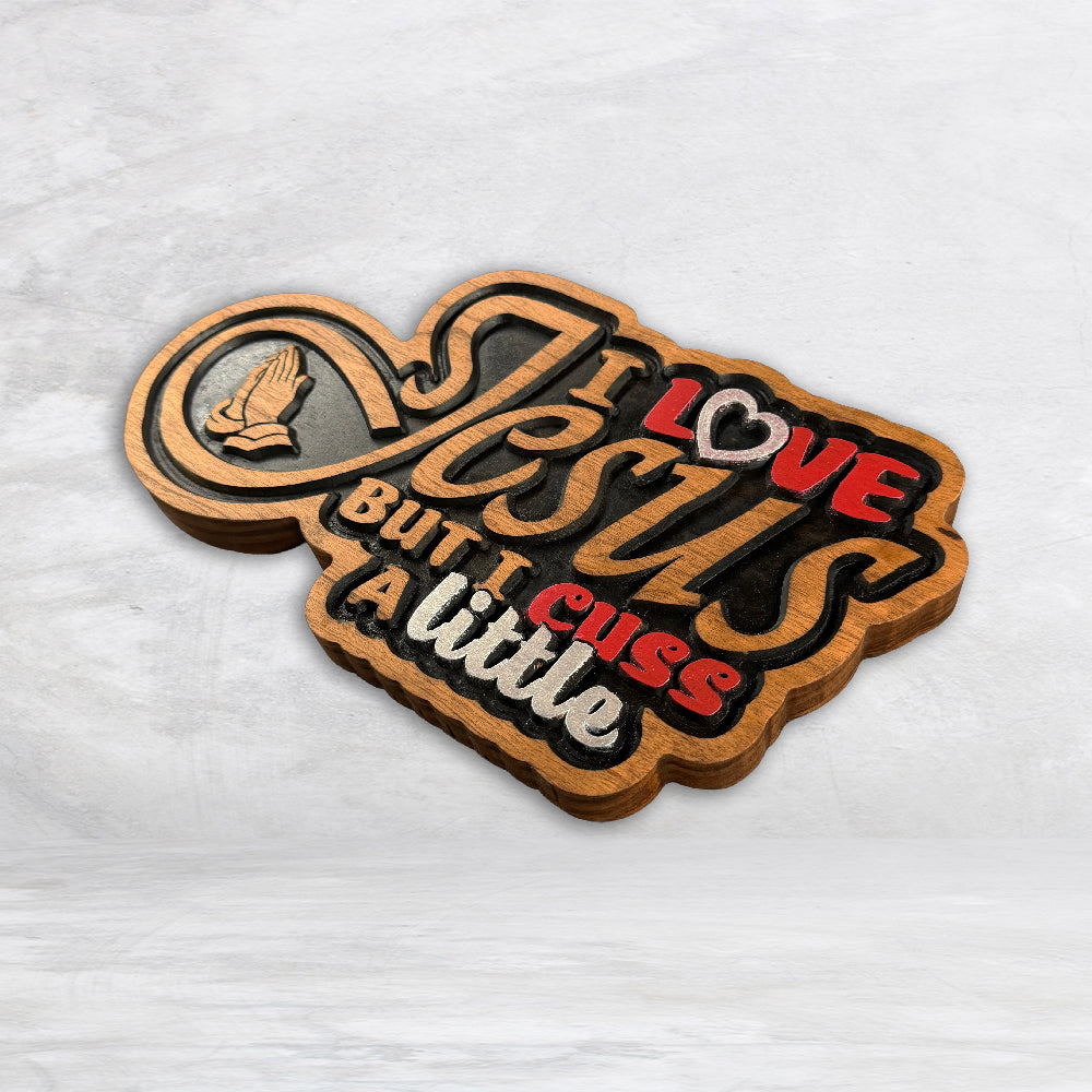 Precision carved cherry wood sign reading I Love Jesus But I Cuss A Little with raised colorful lettering and praying hands made in USA