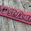 Hand stained purpleheart wood sign featuring precision carved "We" and "St. Louis!" lettering with heart cutout, hand finished unique USA-made wood decor gift.